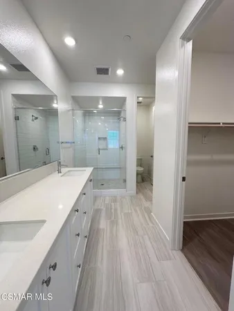 a spacious bathroom with a granite countertop sink a toilet a shower and a mirror