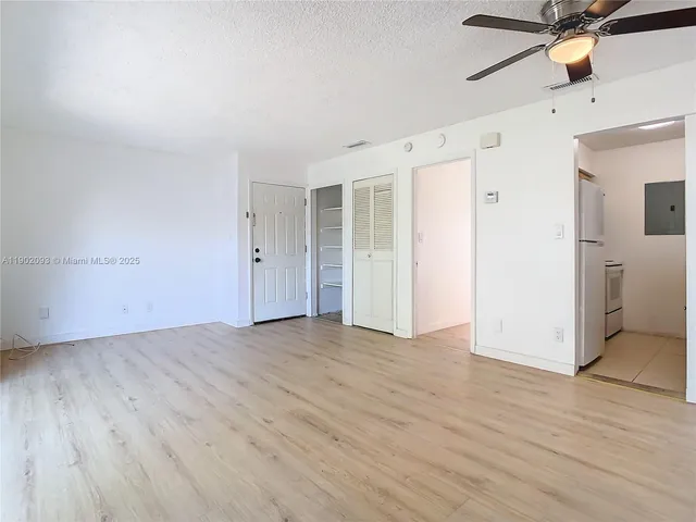 an empty room with wooden floor and a ceiling fan