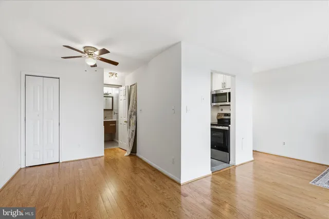 a view of empty room with wooden floor and fan