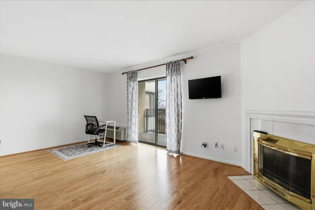 a view of a livingroom with wooden floor and a fireplace