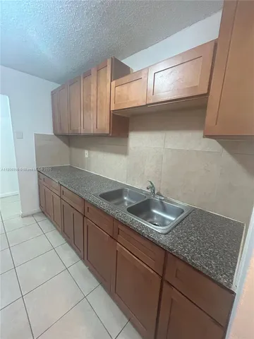 a kitchen with granite countertop a sink a stove and cabinets