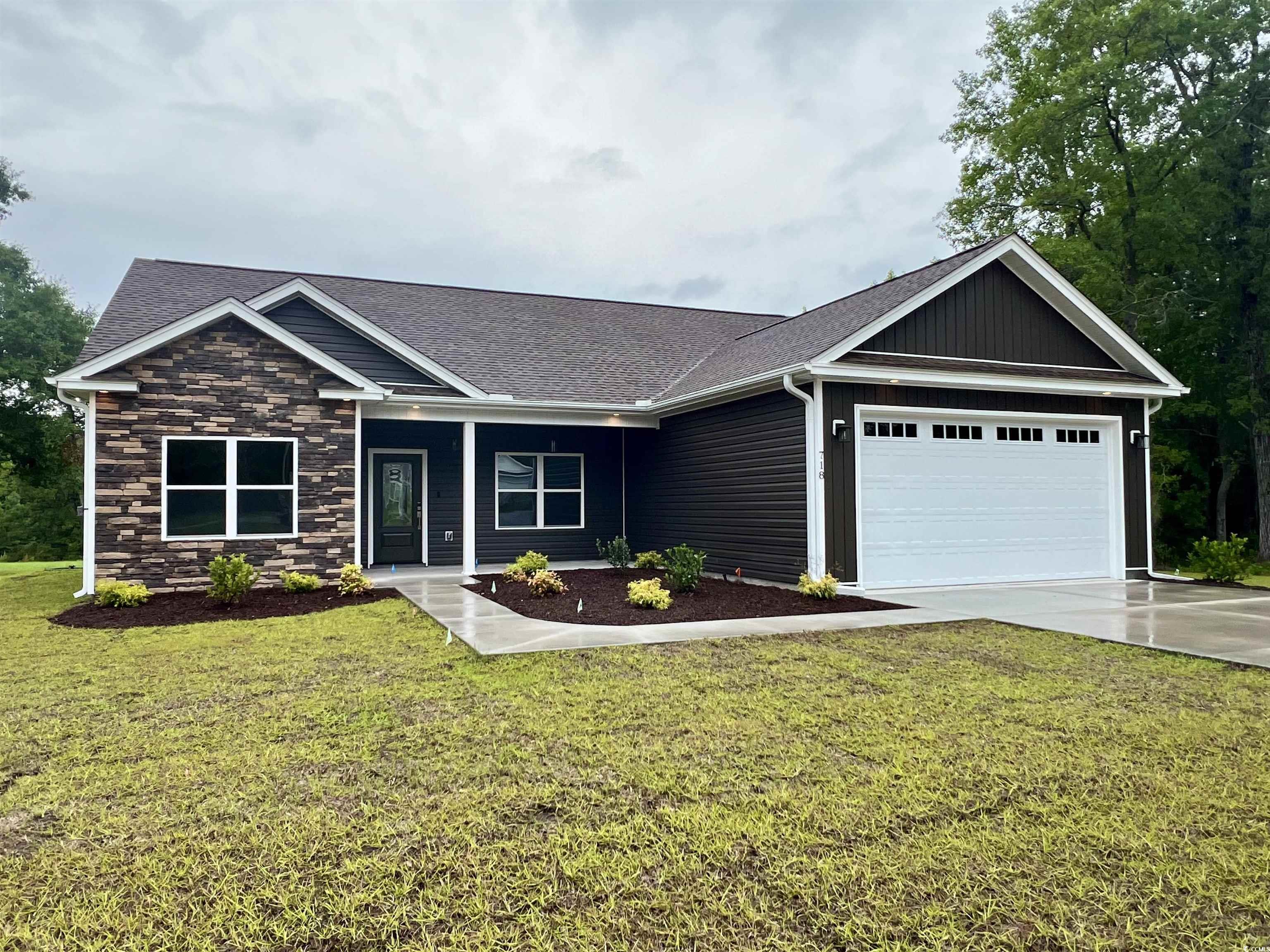 Ranch-style home featuring a garage, a shingled roof, board and batten siding, and a front yard