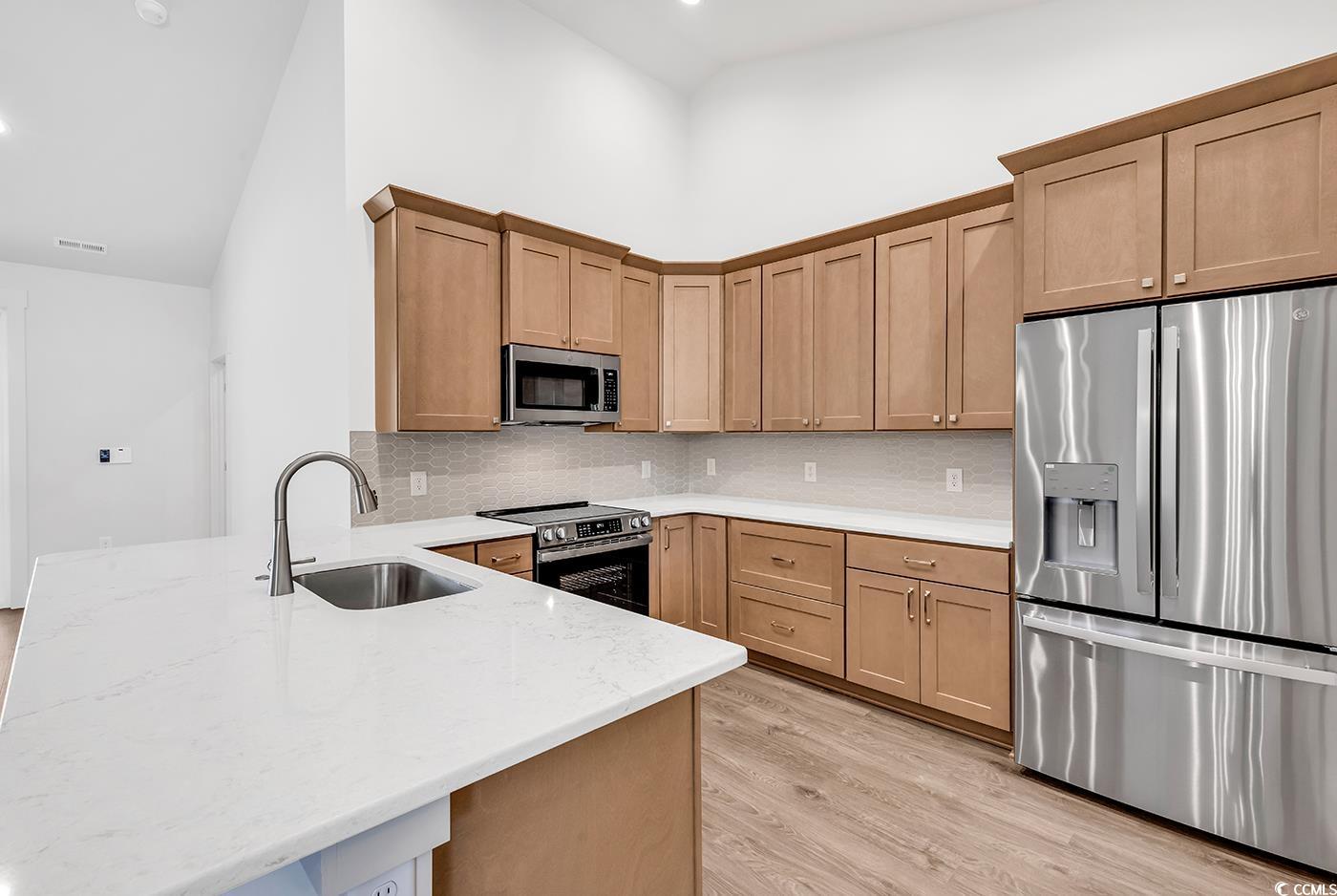 718 Highway 348 Loris, SC 29569 - Photo 14 of 28 Kitchen featuring solid wood cabinetry with soft close doors and drawers, decorative tile backsplash, a single bowl sink, quartz countertops, a peninsula, and stainless steel appliances