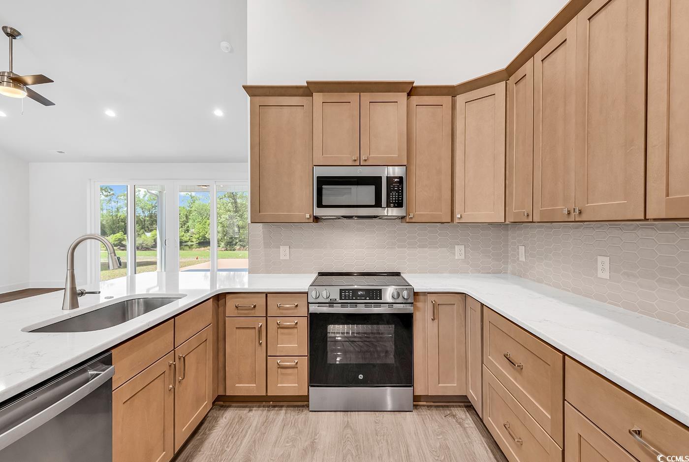 718 Highway 348 Loris, SC 29569 - Photo 15 of 28 Kitchen featuring a single bowl sink, decorative tile backsplash, appliances with stainless steel finishes, and wood laminate flooring
