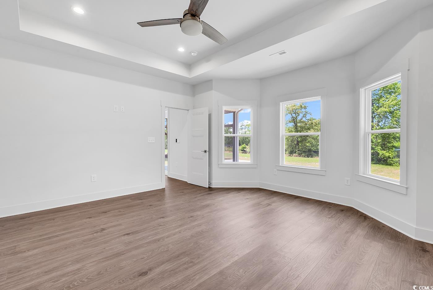 718 Highway 348 Loris, SC 29569 - Photo 19 of 28 Primary Bedroom with bay window, a tray ceiling, recessed lighting, ceiling fan, wide baseboards and door trim, and wood laminate flooring