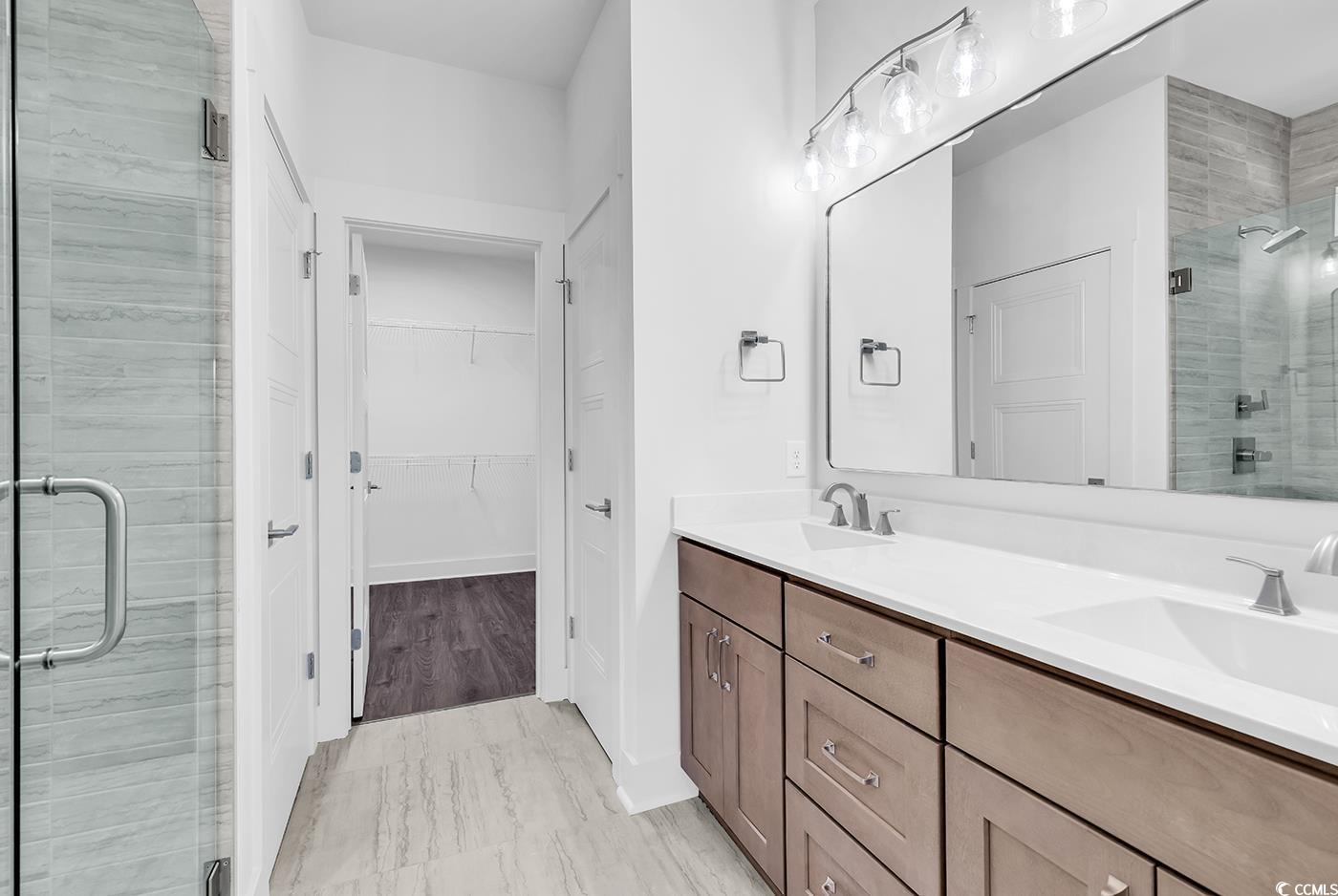 718 Highway 348 Loris, SC 29569 - Photo 20 of 28 Primary Bathroom with dual sink vanity, a spacious closet, private water closet, linen closet, a tiled shower with rain shower head and frameless glass door