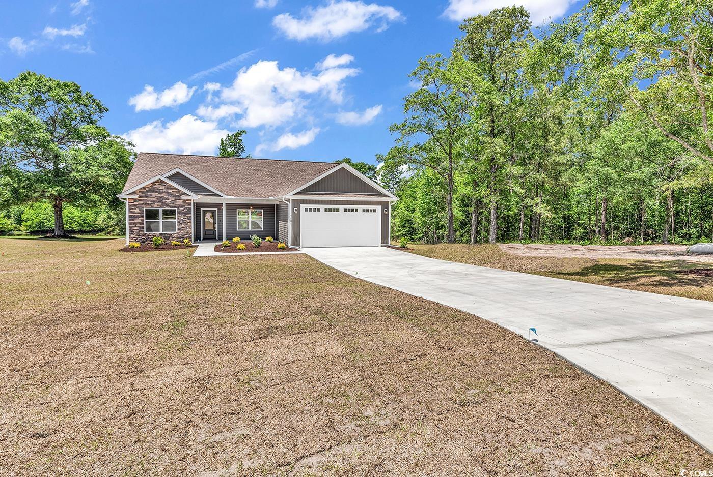 718 Highway 348 Loris, SC 29569 - Photo 2 of 28 Ranch-style house featuring a front porch, with attached 2-car garage, concrete driveway, a front lawn, and stacked stone treatment.