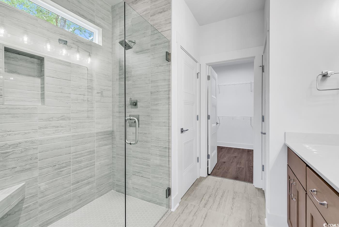 718 Highway 348 Loris, SC 29569 - Photo 21 of 28 Primary Bath featuring a tiled shower with rain shower head, frameless glass door, dual sink vanity, a walk in closet, linen closet and a private water closet.