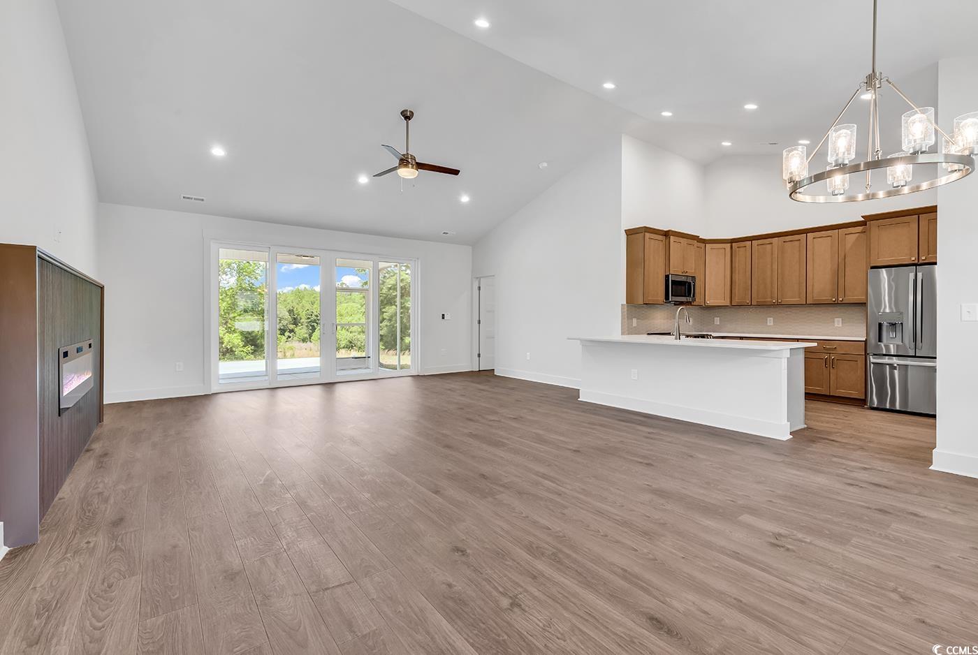 718 Highway 348 Loris, SC 29569 - Photo 8 of 28 Open concept Living Room featuring wood laminate finished flooring, high vaulted ceiling, ceiling fan, with notable Dining area chandelier, and wide baseboards and door trim
