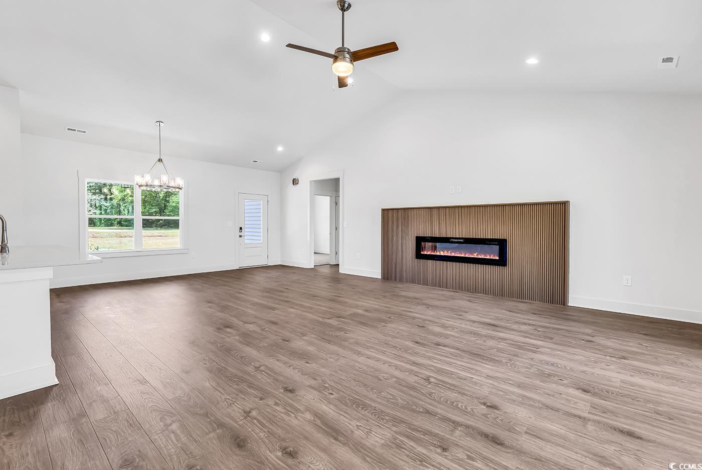 718 Highway 348 Loris, SC 29569 - Photo 9 of 28 Open concept Living Room featuring recessed lighting, a glass covered fireplace, ceiling fan, with notable Dining area chandelier, and wood laminate flooring