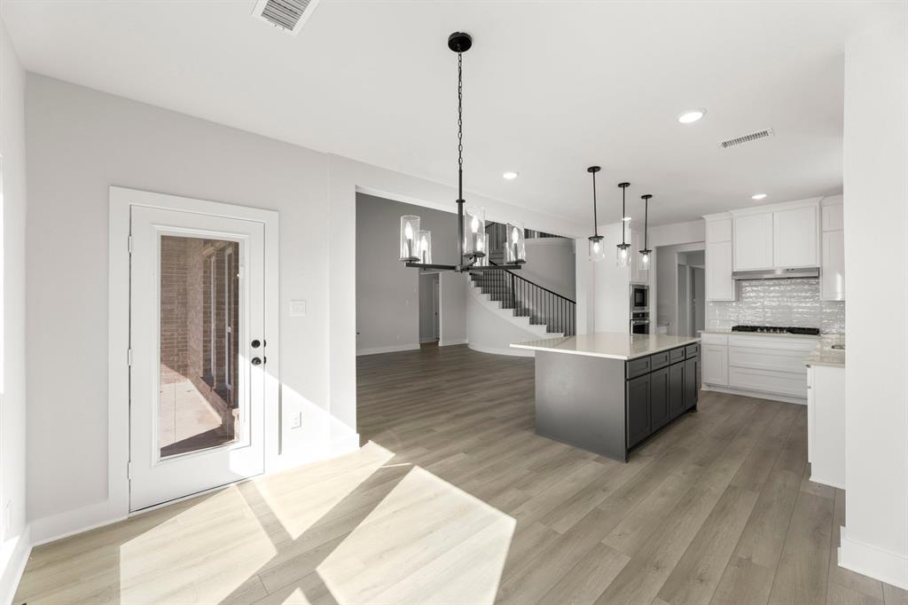 1285 Flamingo Road Forney, TX 75126 - Photo 11 of 40 a large kitchen with kitchen island white cabinets and stainless steel appliances