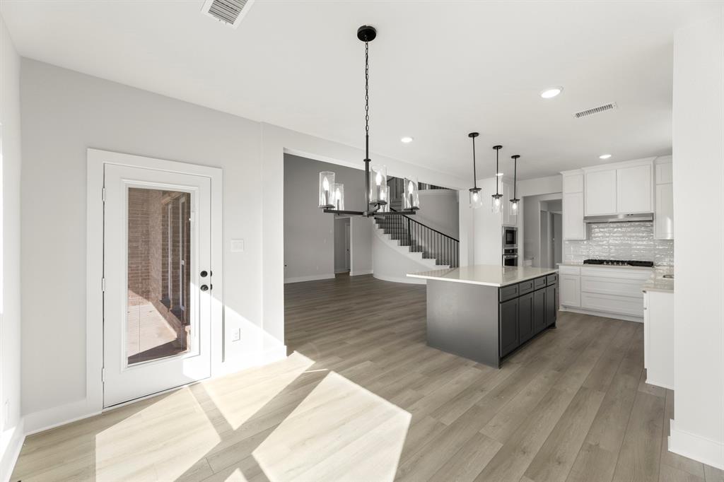 1285 Flamingo Road Forney, TX 75126 - Photo 25 of 40 a large kitchen with kitchen island white cabinets and stainless steel appliances