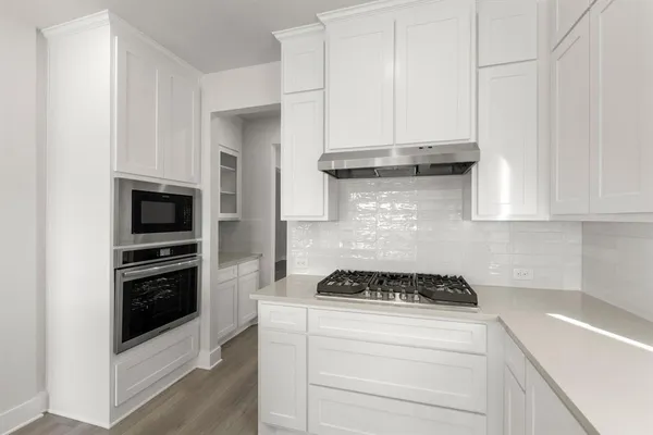 a kitchen with granite countertop white cabinets and stainless steel appliances
