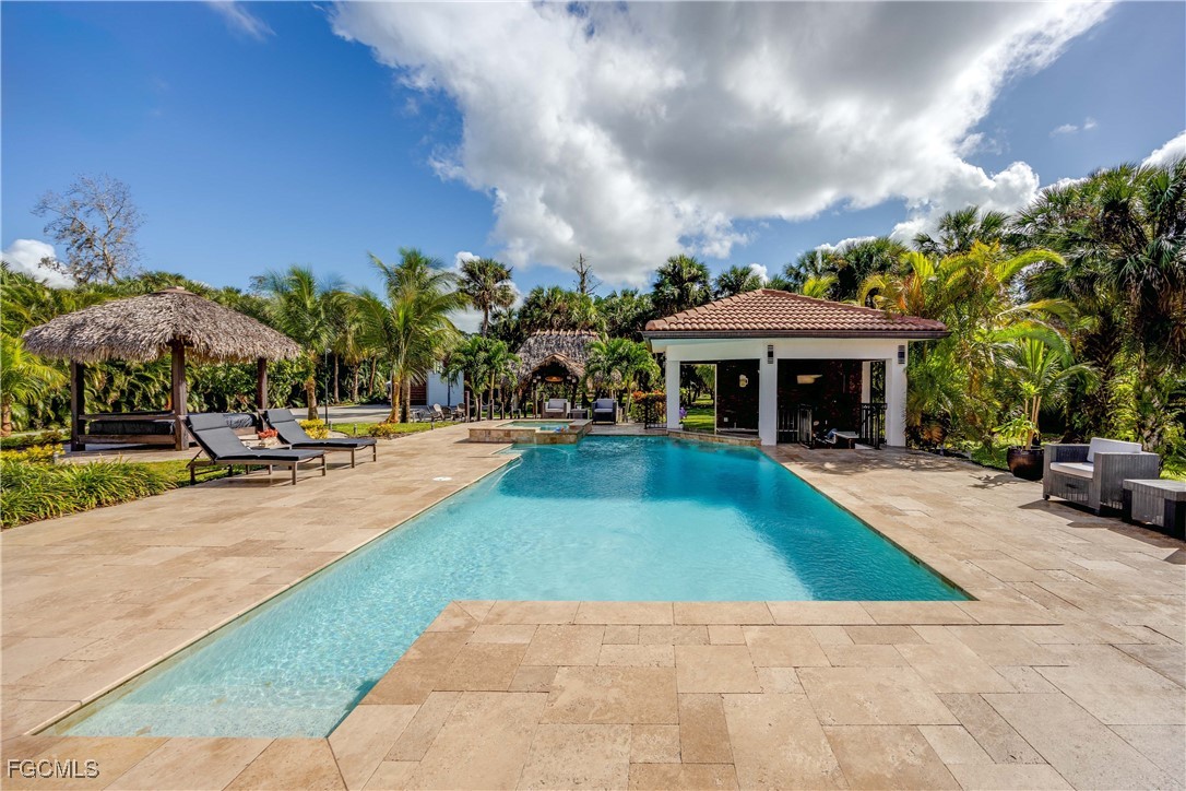 214 9th Street Northwest Naples, FL 34120 - Photo 35 of 49 a view of a swimming pool with lawn chairs under an umbrella