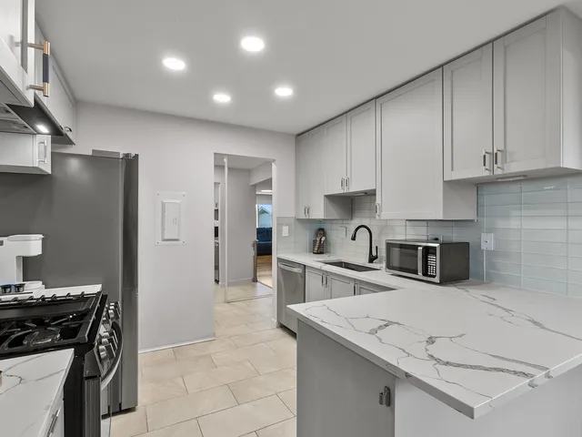 a kitchen with stainless steel appliances granite countertop a sink stove and refrigerator