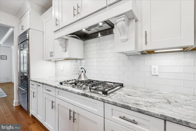 a kitchen with stainless steel appliances granite countertop white cabinets and a stove