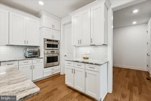 a kitchen with stainless steel appliances granite countertop a stove and white cabinets