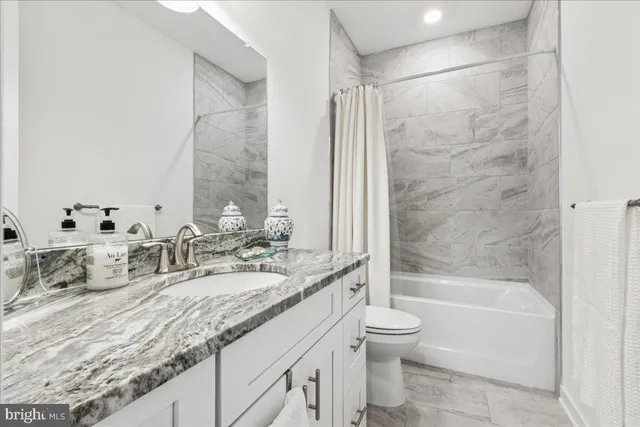 a bathroom with a granite countertop sink a toilet and bathtub