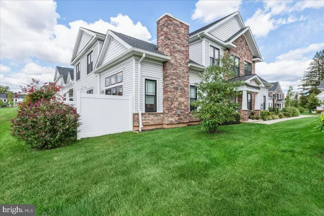 a view of a white house next to a yard with big trees