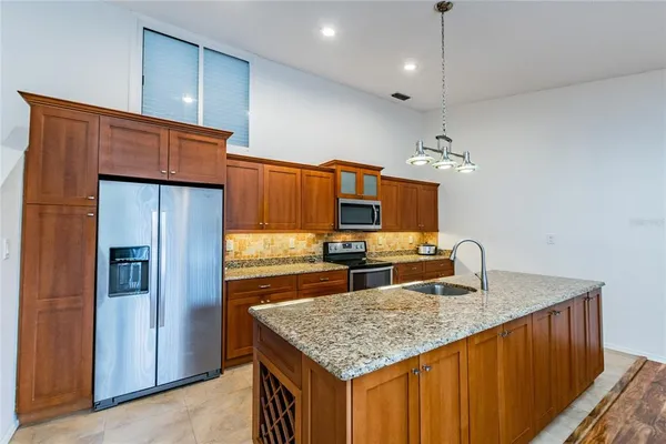 a kitchen with kitchen island granite countertop a sink cabinets and refrigerator