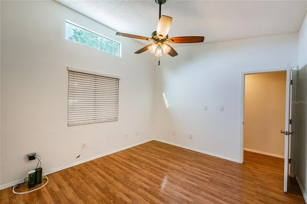 a view of empty room with wooden floor and fan