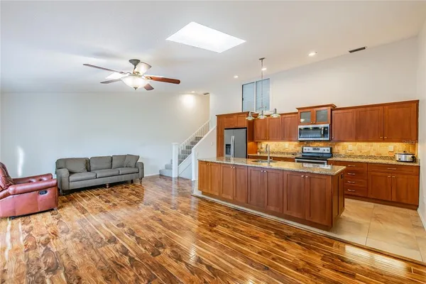 a living room with couches kitchen view and a refrigerator