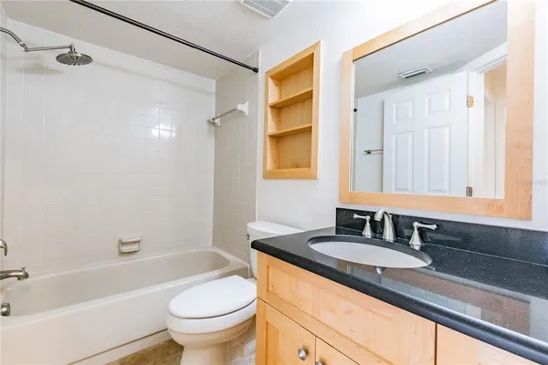 a bathroom with a granite countertop sink a toilet a shower and a mirror