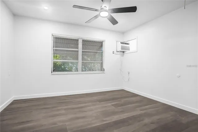 an empty room with wooden floor ceiling fan and windows