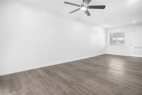 an empty room with wooden floor fan and windows