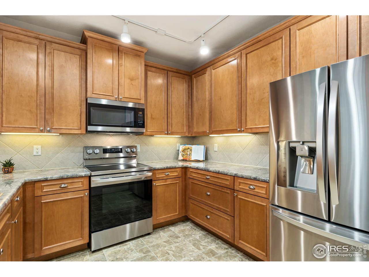 4672 West 20th Road, Unit 2212 Greeley, CO 80634 - Photo 18 of 40 Crown molding accents the natural maple wood grain of the abundant cabinets and the stainless steel of the appliances gives the kitchen a modern feel.