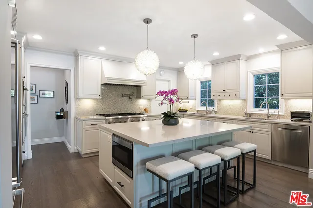 a kitchen with stainless steel appliances a table chairs sink and stove top oven
