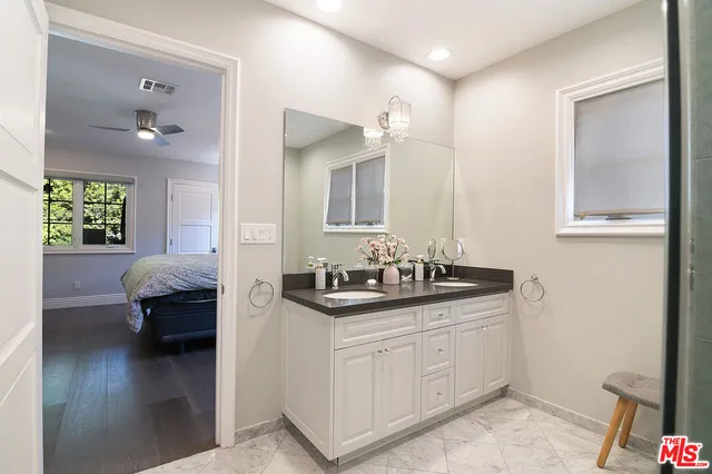 a en suite bathroom with a granite countertop sink and a mirror