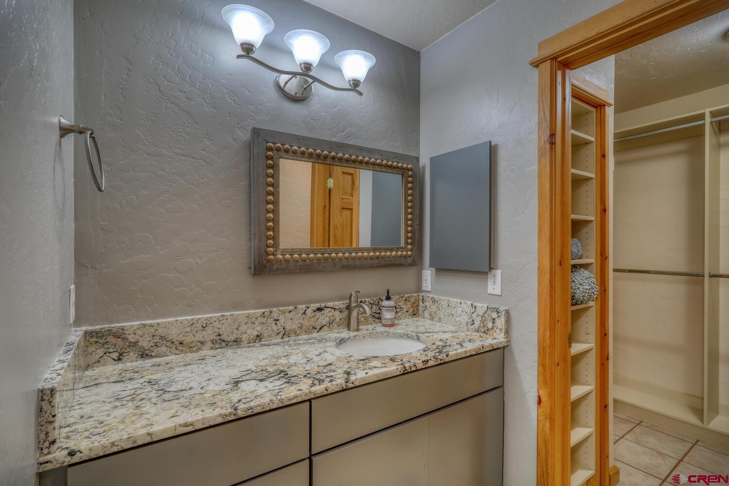569 Eight Mile Loop Pagosa Springs, CO 81147 - Photo 19 of 31 a bathroom with a granite countertop sink and a mirror