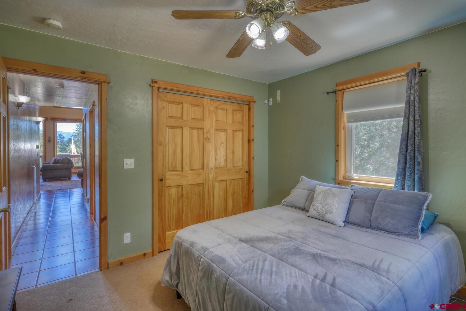 569 Eight Mile Loop Pagosa Springs, CO 81147 - Photo 20 of 31 a bedroom with a large bed and a chandelier