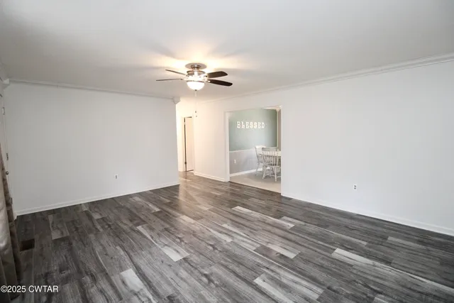 a view of empty room with wooden floor and ceiling fan