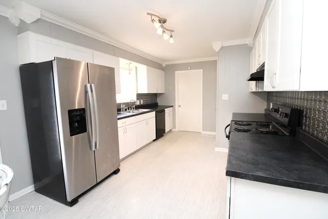 a kitchen with stainless steel appliances granite countertop a refrigerator a stove a sink and a microwave