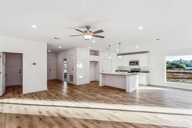 a view of kitchen with stainless steel appliances kitchen island a sink dishwasher a refrigerator and a fireplace with wooden floor