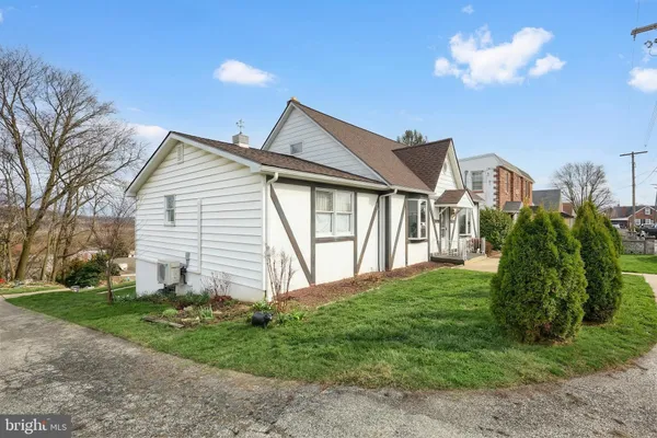 a view of a house next to a yard with big trees