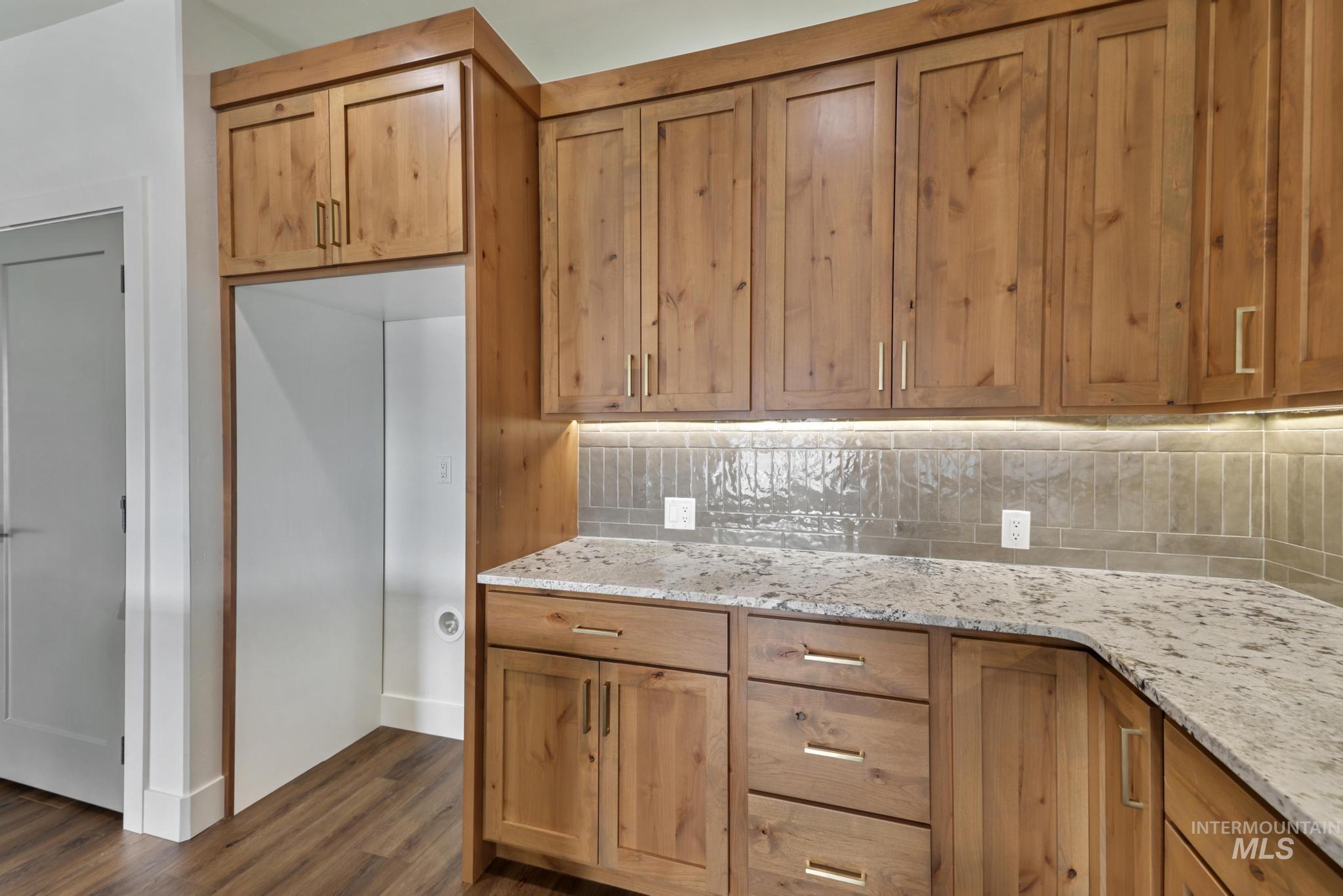 527 Falling Leaf Lane Twin Falls, ID 83301 - Photo 15 of 42 Kitchen featuring light stone counters, dark wood-type flooring, and decorative backsplash