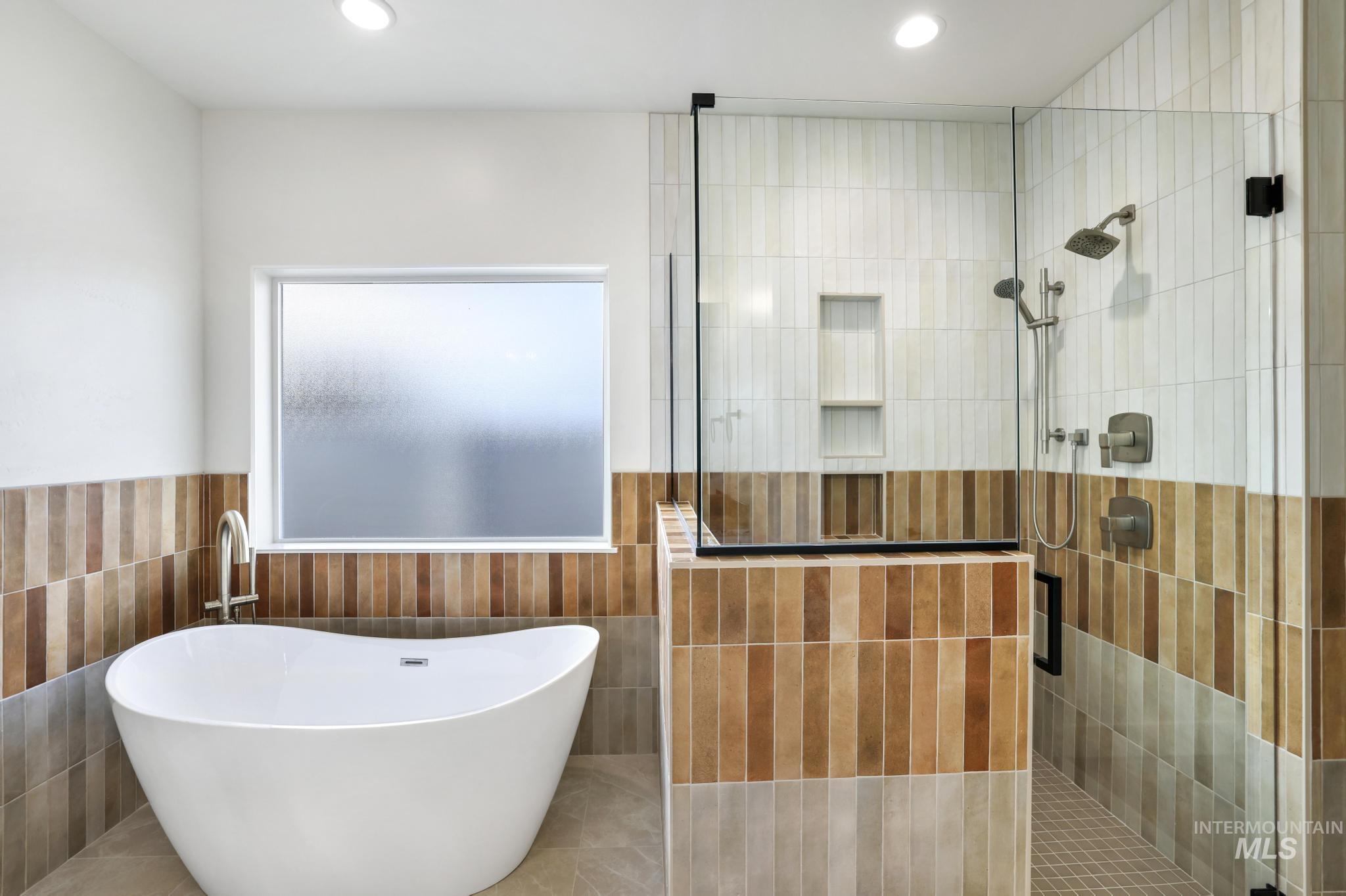527 Falling Leaf Lane Twin Falls, ID 83301 - Photo 25 of 42 Bathroom with a walk in shower, a freestanding tub, wainscoting, recessed lighting, and tile walls