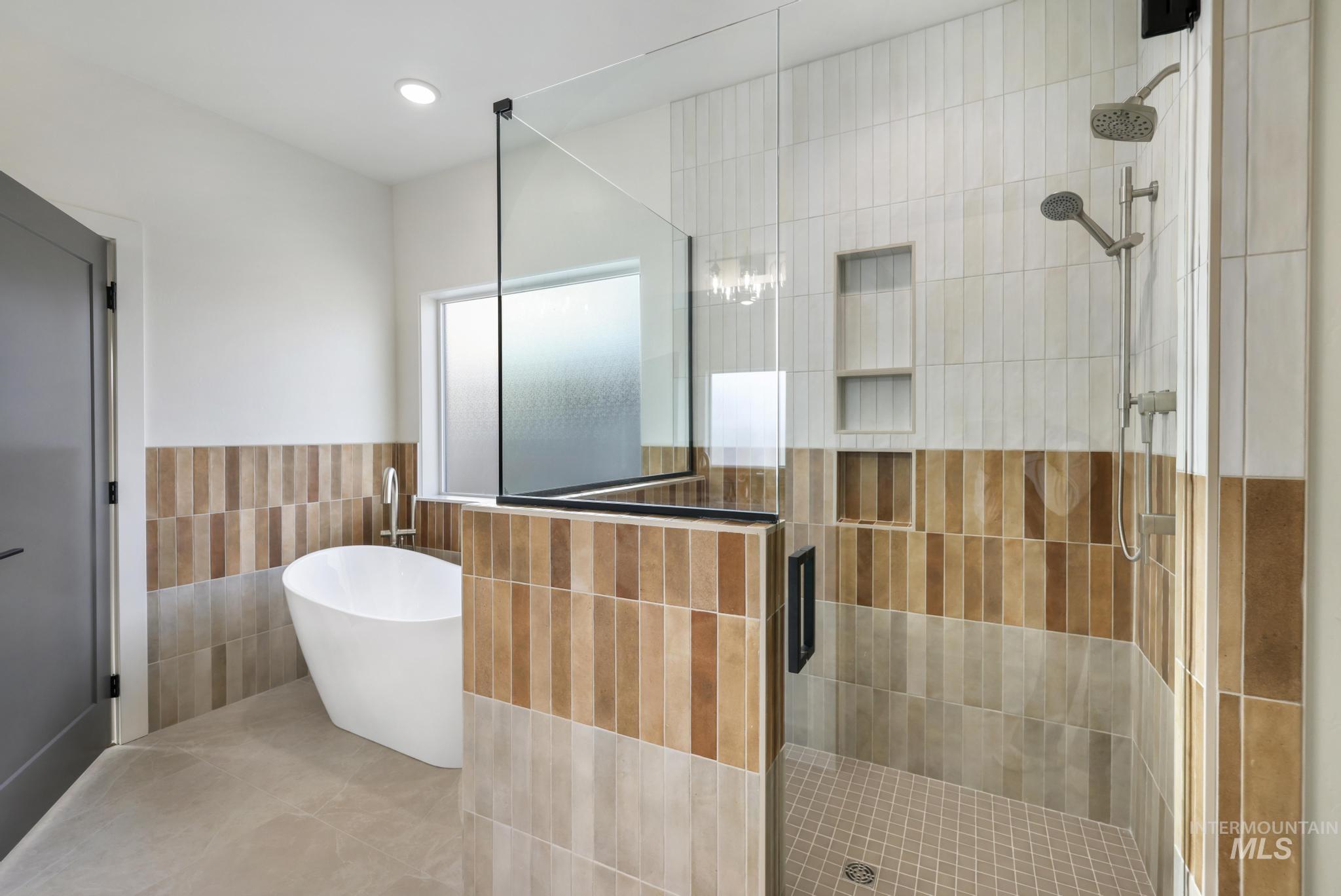 527 Falling Leaf Lane Twin Falls, ID 83301 - Photo 26 of 42 Bathroom featuring tile walls, a shower stall, a freestanding tub, a wainscoted wall, and recessed lighting