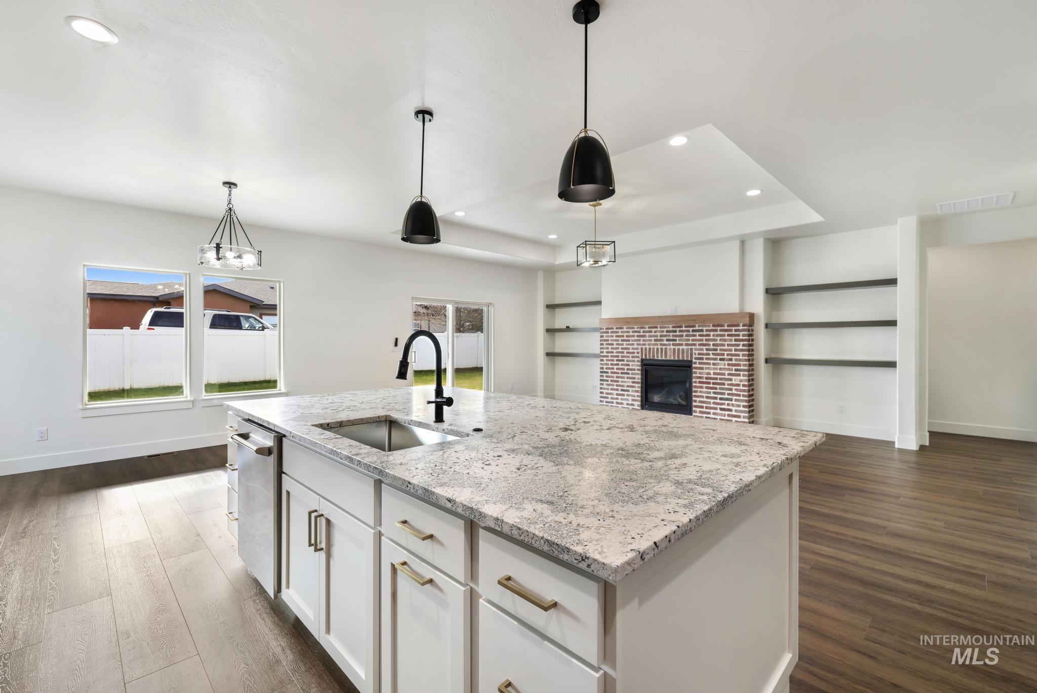 527 Falling Leaf Lane Twin Falls, ID 83301 - Photo 7 of 42 Kitchen with a brick fireplace, white cabinetry, light stone counters, pendant lighting, and recessed lighting