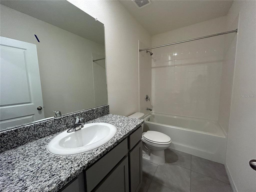 17550 Crescent Moon Loop Bradenton, FL 34211 - Photo 22 of 36 a bathroom with a granite countertop sink a toilet a mirror and shower
