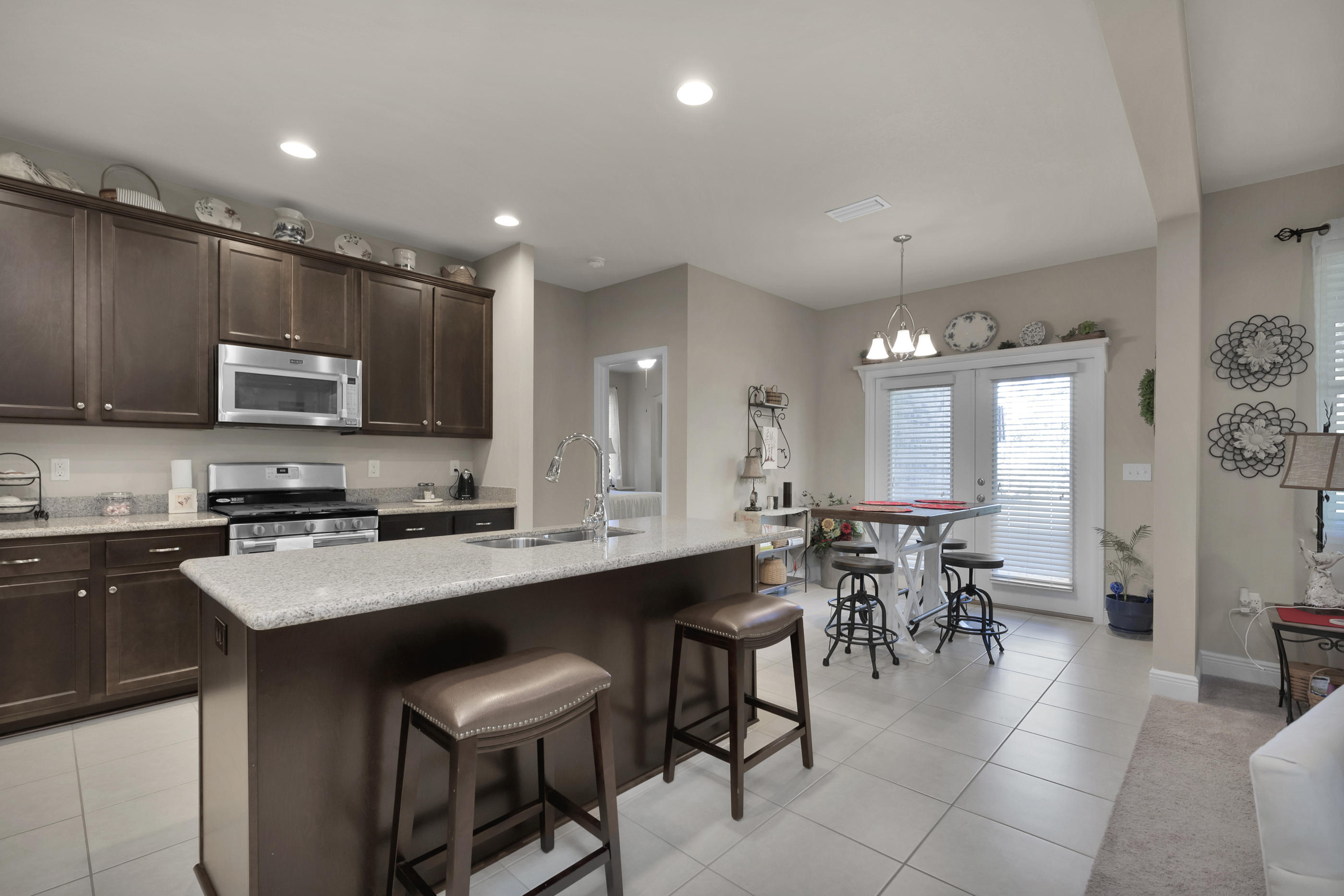 514 Brighton Cove Freeport, FL 32439 - Photo 8 of 32 a group of chairs sitting in a kitchen with kitchen island stainless steel appliances refrigerator stove dining table and chairs