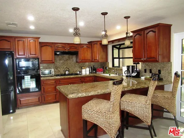 a kitchen with stainless steel appliances granite countertop a stove a sink and a refrigerator