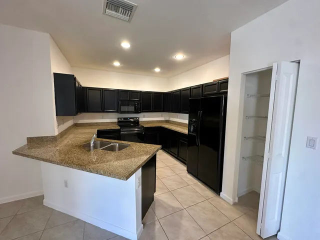 a kitchen with stainless steel appliances granite countertop a sink and a refrigerator