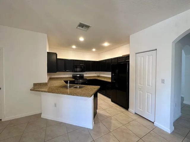 a kitchen with stainless steel appliances granite countertop a sink and a refrigerator
