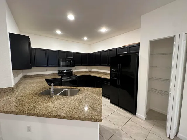 a kitchen with kitchen island granite countertop a refrigerator and a sink