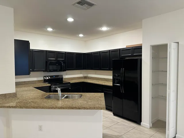 a living room with stainless steel appliances kitchen island granite countertop a refrigerator and a sink