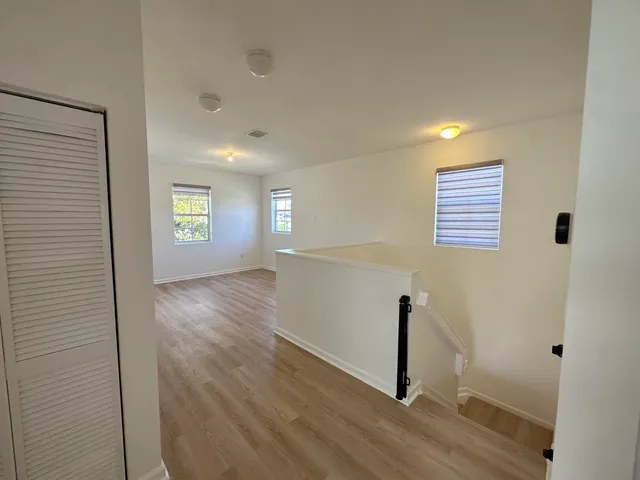 a view of empty room with wooden floor and fan